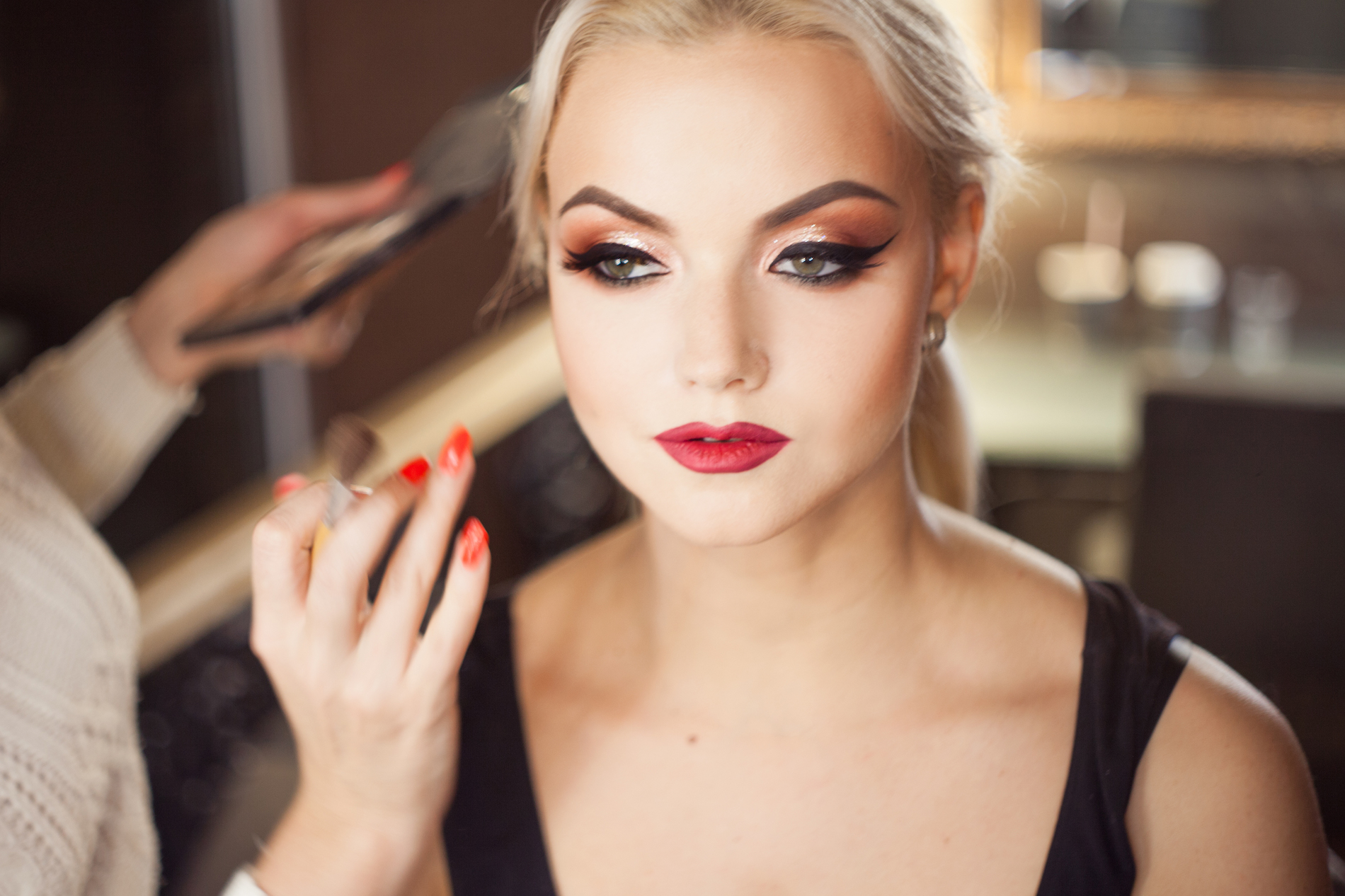 Beautiful young blonde. Makeup artist makes a stylish makeup.